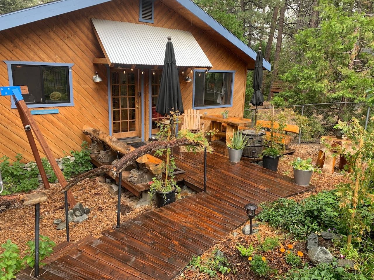 A wooden cabin with a deck, outdoor seating, and potted plants.