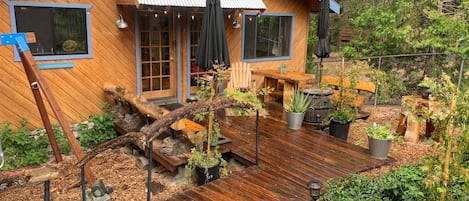 A wooden cabin with a deck, outdoor seating, and potted plants.