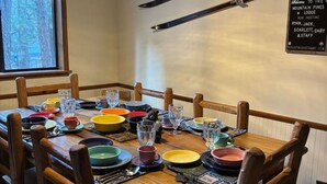 Un comedor con una mesa de madera dispuesta para seis, sillas y un letrero en la pared.