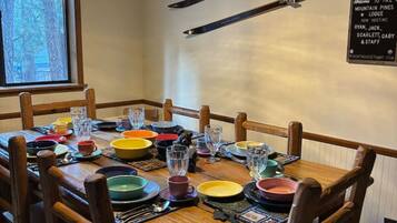 Un comedor con una mesa de madera dispuesta para seis, sillas y un letrero en la pared.