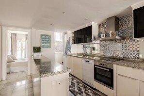 A modern kitchen with a central island, stainless steel appliances, and patterned backsplash tiles. - Cosy Apartment inside Puerto Marina, steps to the Sea (Benalmádena)