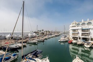 A marina with multiple boats docked, a white building with balconies, and a clear sky. - Cosy Apartment inside Puerto Marina, steps to the Sea (Benalmádena)