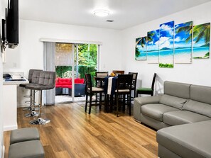 A modern living room with a grey sofa, a red couch, and a dining area with a table and chairs. - LEIRA HOMES • Spacious 3BR Near Florida Keys • Free Parking (Florida City)