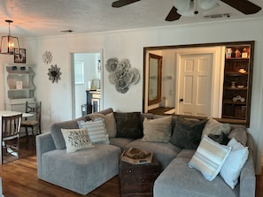 A living room with a sectional sofa, a dining area with a table and chairs, and a bookshelf. - Fabulous 2-bedroom house with AC in charming River Oaks (River Oaks)