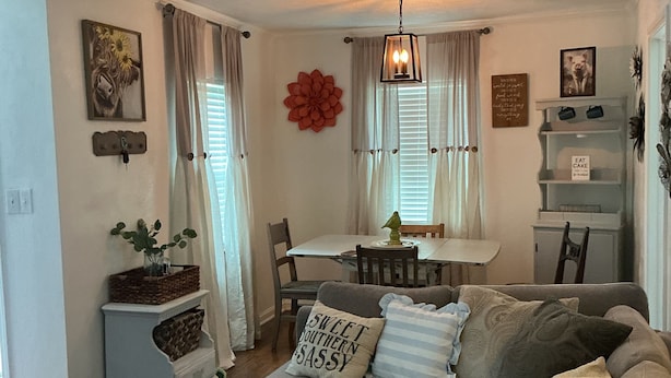 Una sala de estar con un sofá, una mesa de comedor con sillas y una zona de cocina al fondo.
