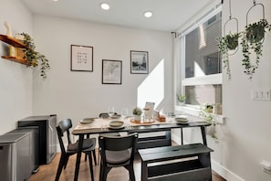 A dining area with a table set for four, chairs, a small refrigerator, and hanging plants. - Family-Friendly 3BR/3.5BA in Fairmount near Center City Philadelphia (Philadelphia)