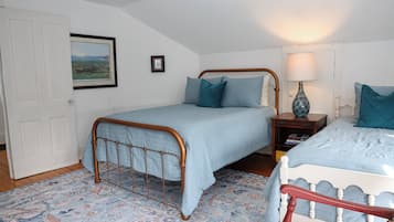 A bedroom with two single beds, a nightstand with a lamp, a framed picture on the wall, and a patterned carpet.