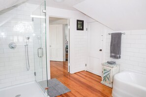 A modern bathroom with a glass shower enclosure, a white bathtub, and a wooden floor. - Spacious 3 bed 2 1/2 bath home on Palacios waterfront. Great views and location. (Palacios)