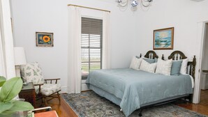 Un dormitorio con una cama, una silla, un tapete y un cuadro en la pared.
