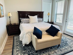 A bedroom with a large bed, two bedside tables, a chair, a patterned rug, and a window with blinds. - Lake Travis Water Front - 180' Water Views  -3 beds and two baths (Jonestown)