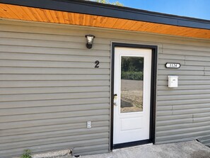 A single-story building with a white door, a mailbox, and a house number '1124' on the wall.