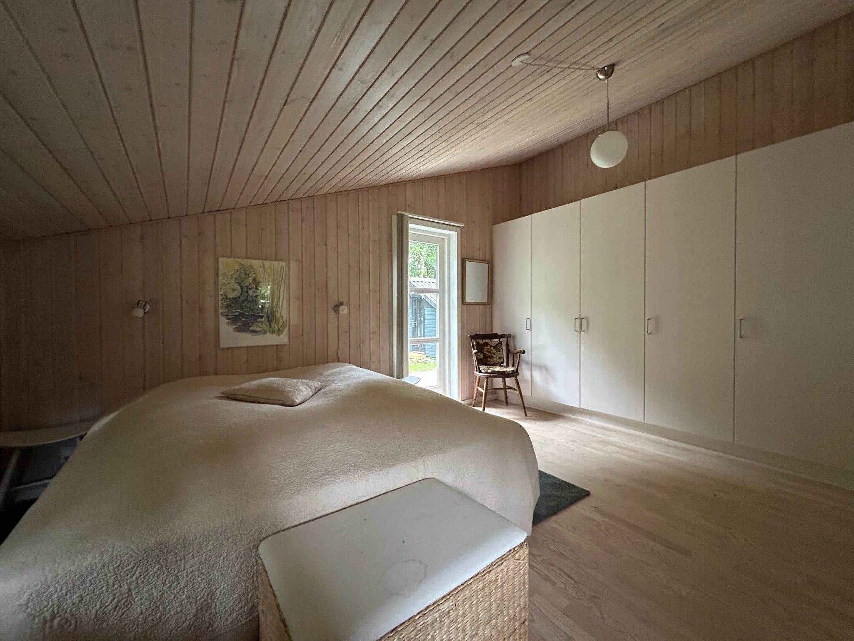 Quarto com cama, cadeira e guarda-roupa.