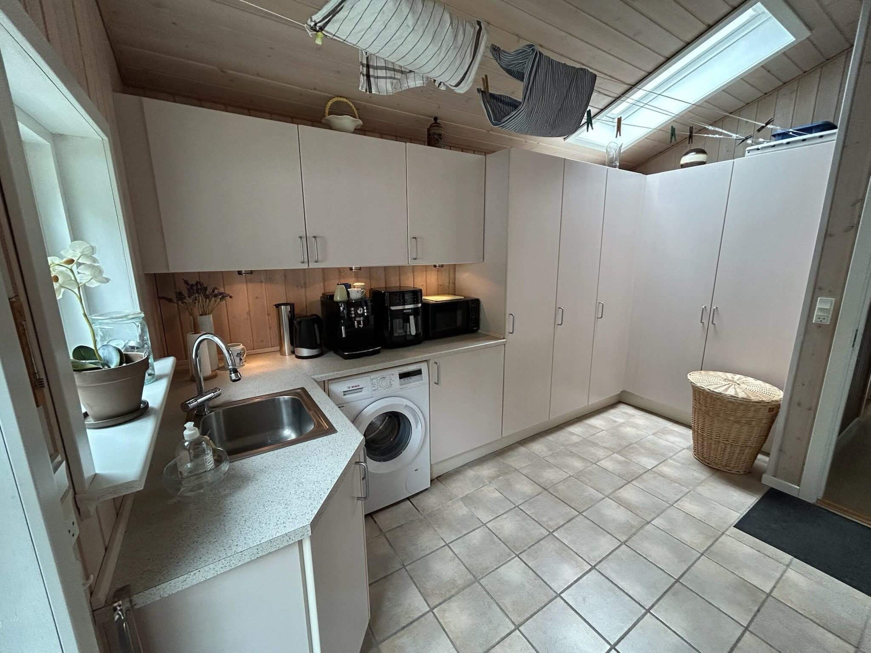 A compact kitchen with a washing machine, a sink, and a coffee maker.