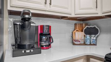 A kitchen with a coffee maker, a kettle, and a coffee grinder on the counter.