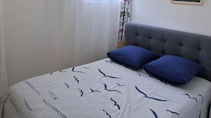 Ein Schlafzimmer mit Bett, einem Fenster mit Vorhängen, einem Bild an der Wand und einer Pendelleuchte.