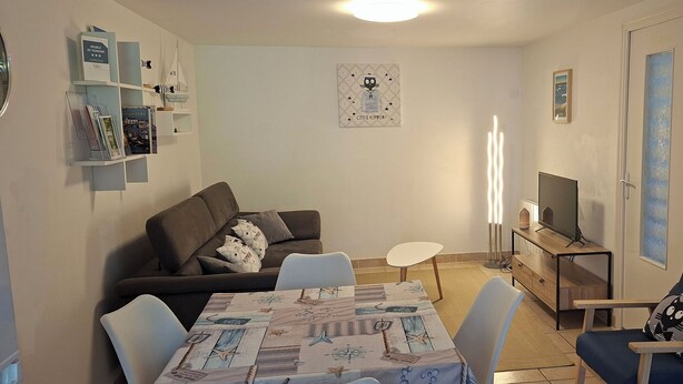 Ein gemütliches Wohnzimmer mit einer Couch, einem Esstisch und einer TV-Konsole.