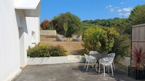 Eine Terrasse mit Tisch und Stühlen, umgeben von Pflanzen und einem Holzzaun.
