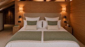 A bedroom with a large bed, wooden headboard, bedside lamps, and a carpeted floor. - SIGA Grand BO Chalet, Sleeps 14–16 — Newly Built and Fully Equipped (Le Grand-Bornand)