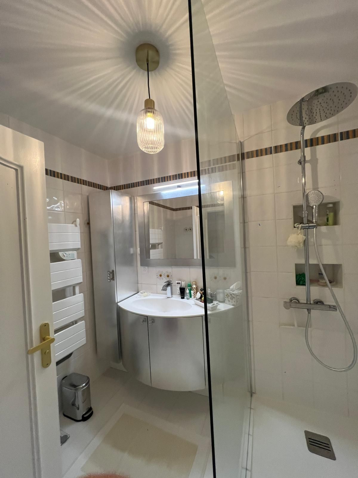 Casa de banho moderna com cabine de duche em vidro, lavatório branco e espelho em cima.