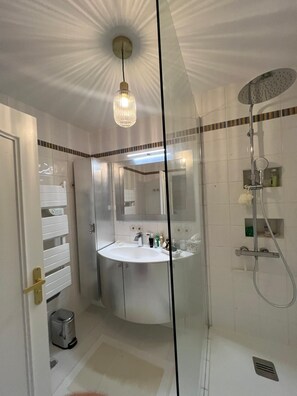 Ein modernes Badezimmer mit Duschkabine aus Glas, einem weißen Waschbecken und einem Spiegel darüber.