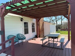 A wooden deck with a pergola, two chairs, and a table. - Happy Homeplace - 1-bedroom farmhouse with AC in charming Bedford (Bedford)
