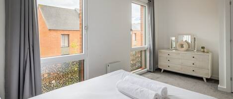 Un dormitorio con cama, cómoda y ventana con cortinas.