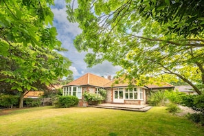 A house with a brick exterior, a tiled roof, and a fenced yard. - Swift Host | Scriveners | Blakeney | Sleeps 12 | Pet Friendly | Free Parking (Blakeney)