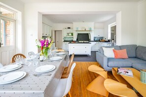Eine moderne Küche mit weißen Schränken, einem eingebauten Backofen und einem Essbereich mit Tisch für vier Personen.