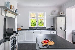Eine moderne Küche mit weißen Schränken, einer schwarzen Arbeitsplatte, einer Spüle und einem Fenster mit Blick auf Grünflächen.