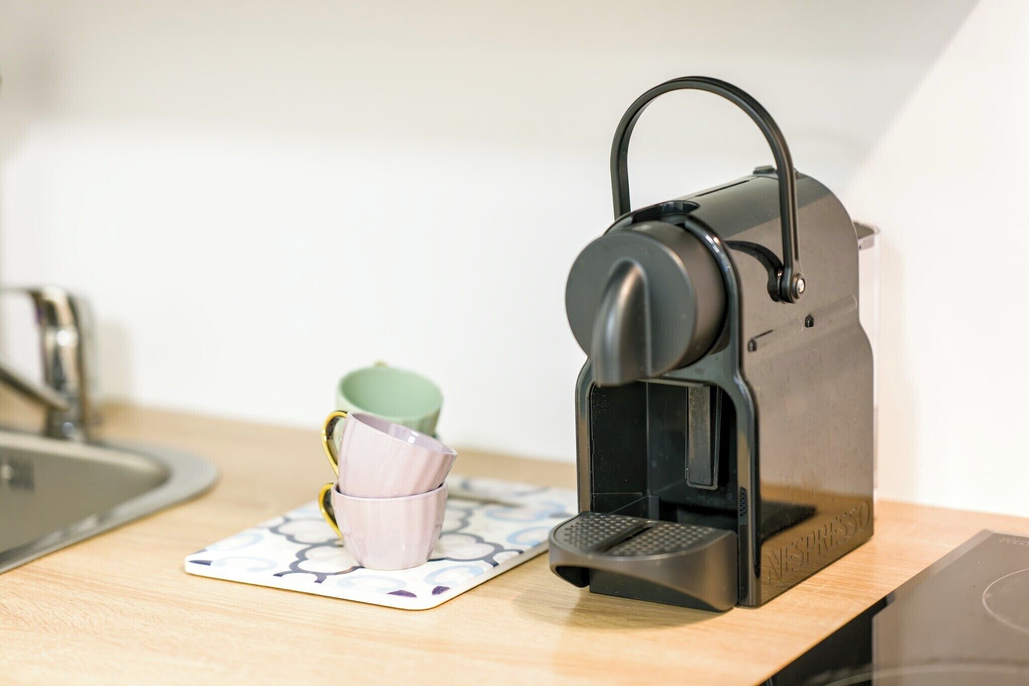 A coffee machine on a kitchen counter with a cup and saucer.