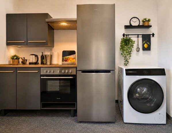 Eine moderne Küche mit einem Edelstahl-Kühlschrank, Backofen und einer Waschmaschine.