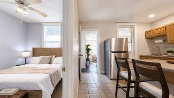 A hotel room with a bed, bedside table, lamp, and a ceiling fan.