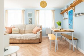 Uma sala de estar aconchegante com um sofá, uma mesa de jantar e um banco.