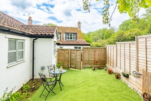 A residential property with a white exterior, a tiled roof, a fenced backyard, and a small patio with a table and chairs. - Swift Host | Holly Lodge | Sleeps 4 | Private Garden | Dog Friendly | Dereham (Dereham)