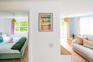 A room with a bed, a bedside table, a window, and a wall-mounted artwork. - Swift Host | Holly Lodge | Sleeps 4 | Private Garden | Dog Friendly | Dereham (Dereham)