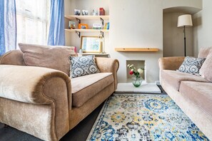 Una sala de estar con dos sofás, una mesa de centro, una estantería y una lámpara.