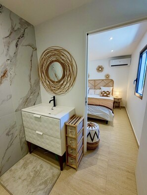 A bathroom with a marble wall, a white sink, and a mirror. - SEA VIEW TINTAMARRE Villa – Brand-new waterfront villa in Oyster Pond (Oyster Pond)
