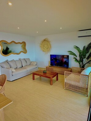 A living room with a sofa, a coffee table, a TV, and a large potted plant. - SEA VIEW TINTAMARRE Villa – Brand-new waterfront villa in Oyster Pond (Oyster Pond)