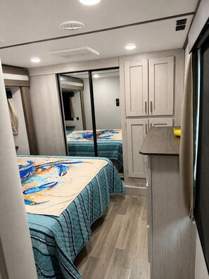 Ein gemütliches Schlafzimmer mit zwei Betten, einer kleinen Küchenzeile und einem Schiebetürenschrank.