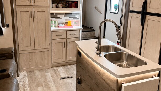 Una cocina moderna con armarios de madera, un lavamanos de acero inoxidable e iluminación colgante.