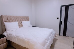 A bedroom with a bed, a nightstand, and a door. - Luxury 3-Bedroom Suite · Gishushu, Kigali (Kigali)