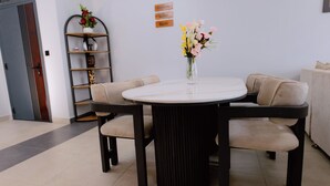 Een eetruimte met een ronde tafel, vier stoelen en een vaas met bloemen.