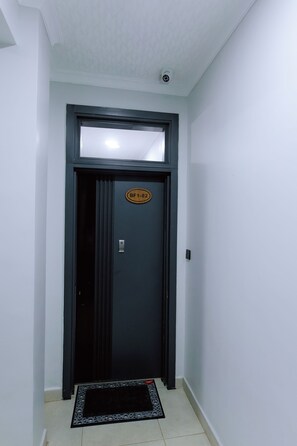 A black door with a window above it, a small plaque with 'BF1-02' on the door, and a black mat at the entrance. - Luxury 3-Bedroom Suite · Gishushu, Kigali (Kigali)