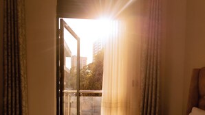 Een hotelkamer met een bed, gordijnen en uitzicht door een glazen deur.
