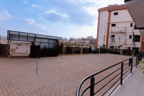A paved outdoor area with a metal railing, a building with scaffolding, and a clear sky. - Luxury 3-Bedroom Suite · Gishushu, Kigali (Kigali)