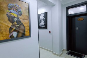 A hallway with two framed artworks on the walls, a door with a sign, and a tiled floor. - Luxury 3-Bedroom Suite · Gishushu, Kigali (Kigali)