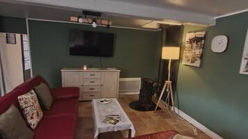 Een woonkamer met een rode bank, een kleine tafel, een televisie en een lamp.