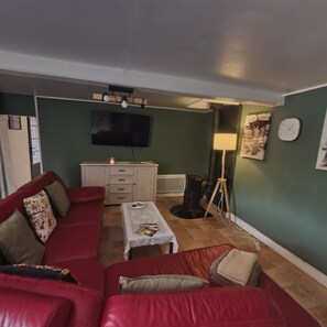 A living room with a red sofa, a small table, a television, and a lamp. - Your own farmfouse (Béalencourt)