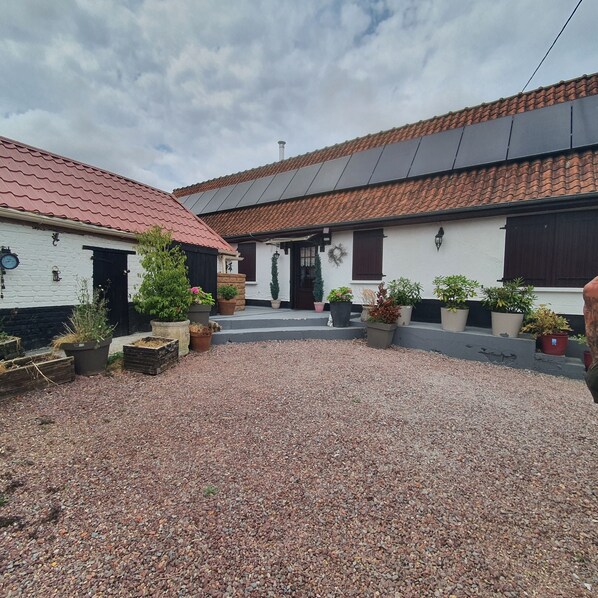 A courtyard with a gravel ground, potted plants, and buildings with red-tiled roofs. - Your own farmfouse (Béalencourt)