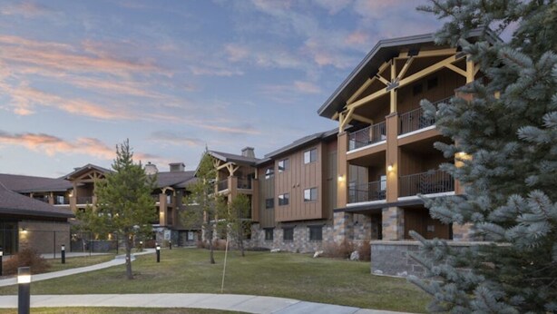 A multi-story hotel with a stone facade, balconies, and a well-maintained lawn. - Cozy 1-bedroom condo in soothing West Yellowstone with AC (West Yellowstone)